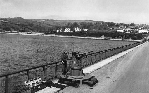 WW2 historical photo of man standing guard of Shaldon Bridge with an artillery rifle.
